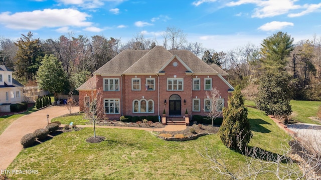 colonial house featuring a front lawn and brick siding