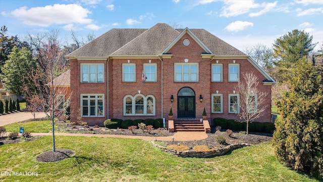 georgian-style home featuring french doors, brick siding, a front yard, and a shingled roof