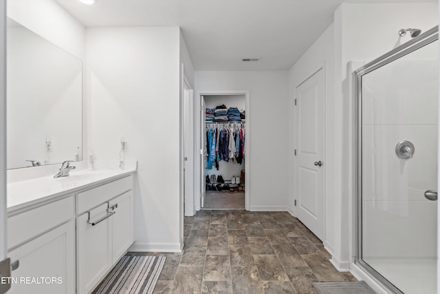 bathroom featuring a shower with door and vanity