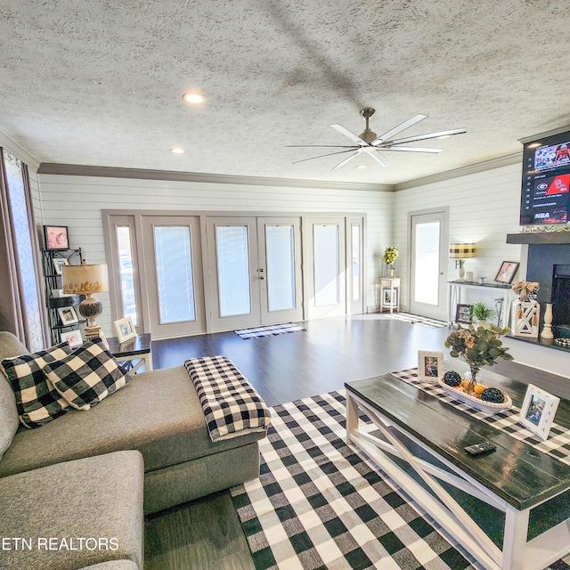 living room featuring ceiling fan, a textured ceiling, and wood walls