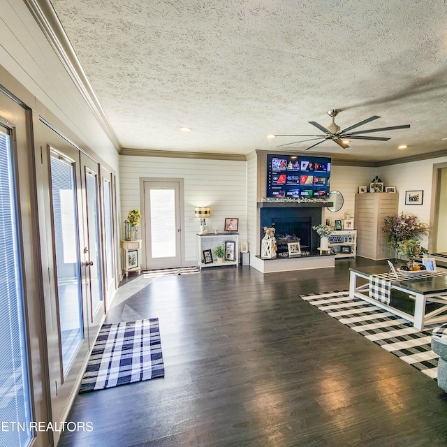 living room featuring ceiling fan, ornamental molding, hardwood / wood-style floors, and a textured ceiling