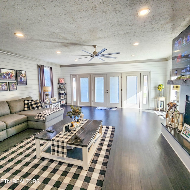 living room featuring dark wood-type flooring, ceiling fan, a textured ceiling, and wood walls