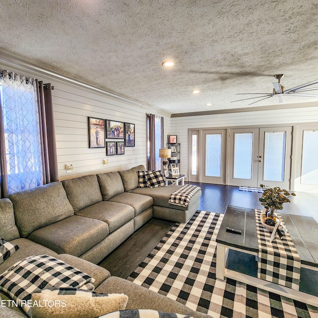 living room featuring ceiling fan, hardwood / wood-style floors, a textured ceiling, and wood walls