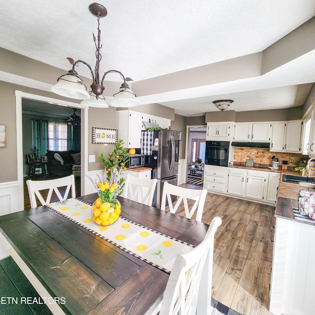 dining area featuring sink, hardwood / wood-style floors, a textured ceiling, and a chandelier