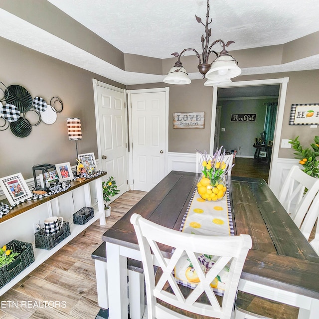 dining room featuring an inviting chandelier, hardwood / wood-style flooring, and a textured ceiling