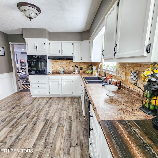 kitchen with white cabinetry, sink, light hardwood / wood-style flooring, and black appliances