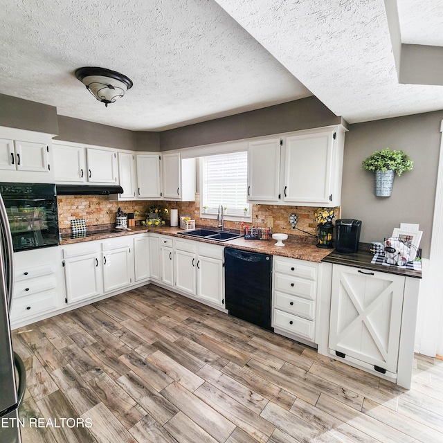 kitchen featuring sink, white cabinetry, backsplash, black appliances, and light hardwood / wood-style floors