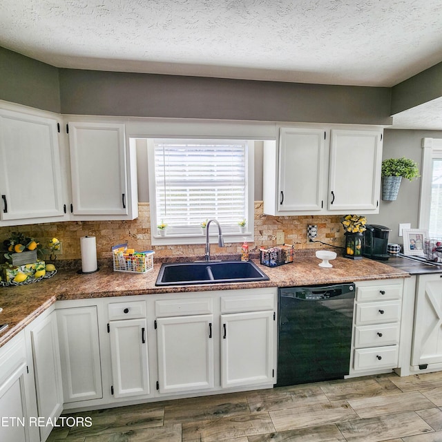 kitchen featuring white cabinetry, black dishwasher, sink, and a textured ceiling