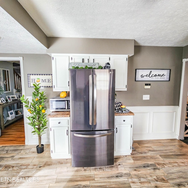 kitchen featuring stainless steel fridge and white cabinets