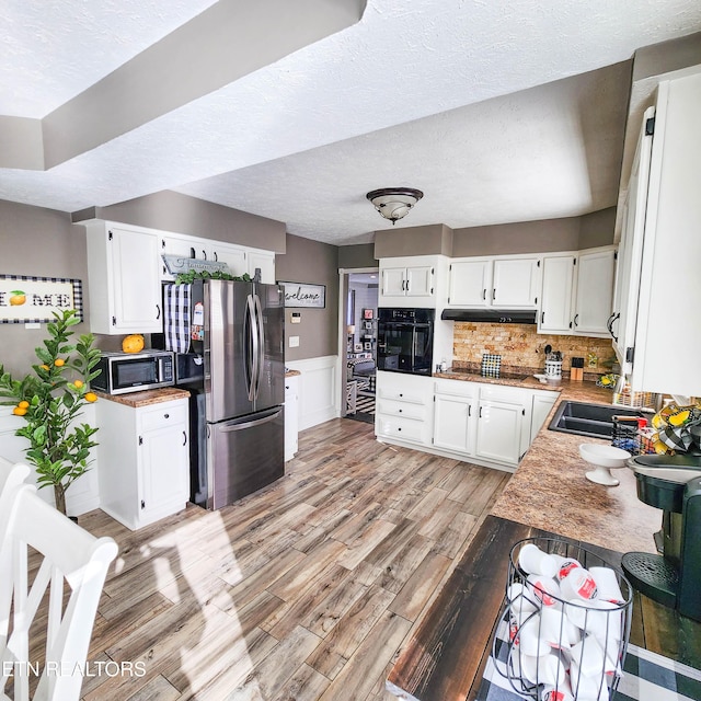 kitchen with white cabinetry, stainless steel appliances, tasteful backsplash, and light wood-type flooring