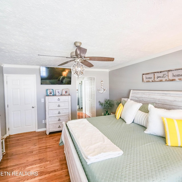 bedroom with hardwood / wood-style floors, a textured ceiling, ornamental molding, and ceiling fan