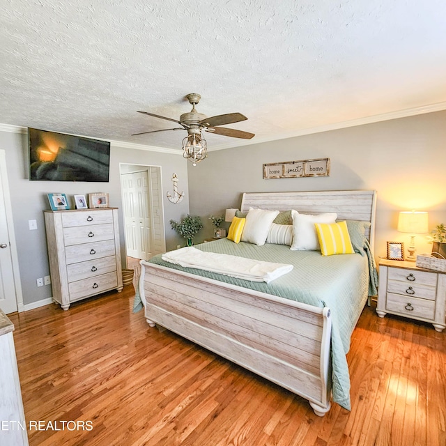 bedroom featuring light hardwood / wood-style flooring, ceiling fan, ornamental molding, a textured ceiling, and a closet