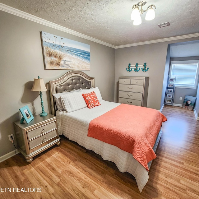 bedroom with hardwood / wood-style flooring, ornamental molding, and a textured ceiling