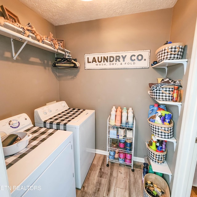 laundry room featuring hardwood / wood-style floors, a textured ceiling, and washing machine and clothes dryer