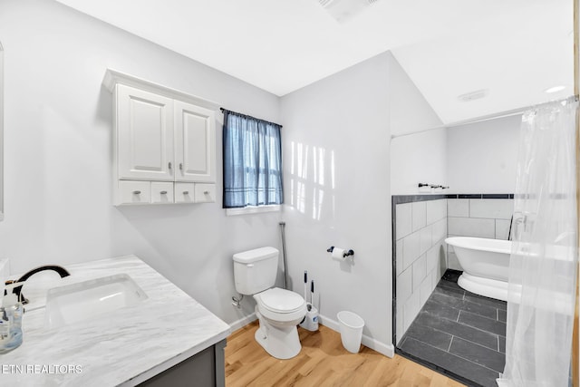 bathroom featuring wood-type flooring, vanity, a bath, and toilet