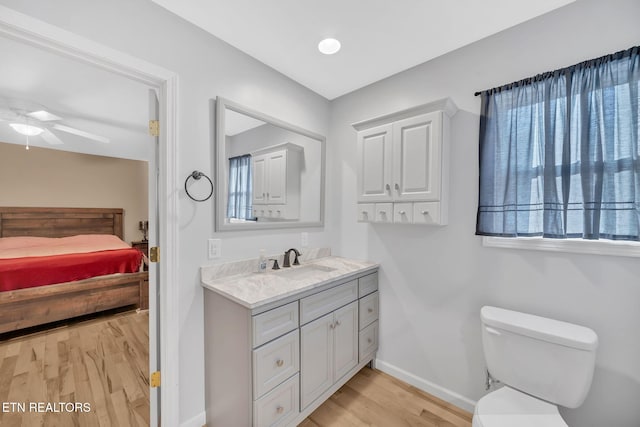 bathroom with wood-type flooring, vanity, toilet, and ceiling fan