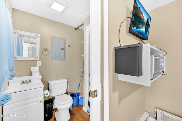 bathroom with electric panel, hardwood / wood-style floors, vanity, and toilet