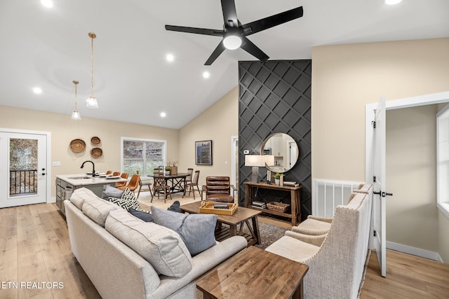 living room featuring an accent wall, light wood-type flooring, visible vents, and baseboards