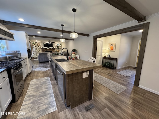 kitchen featuring sink, stainless steel appliances, a kitchen island with sink, a fireplace, and white cabinets