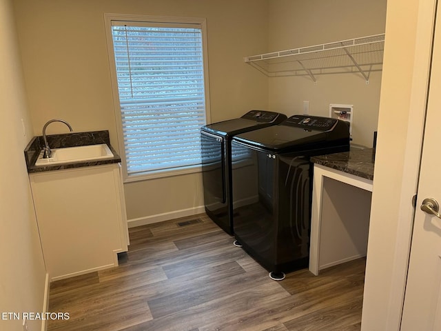 laundry area with dark hardwood / wood-style flooring, separate washer and dryer, and sink