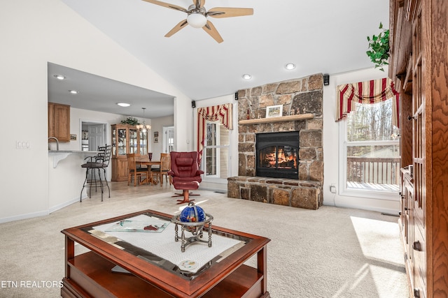 carpeted living room featuring a fireplace, high vaulted ceiling, ceiling fan with notable chandelier, and sink