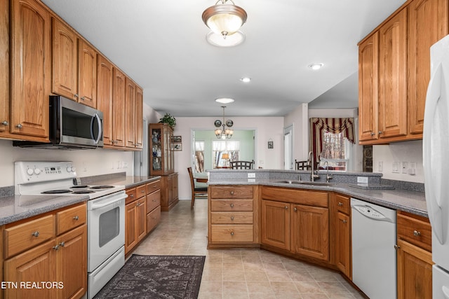 kitchen featuring sink, an inviting chandelier, kitchen peninsula, pendant lighting, and white appliances