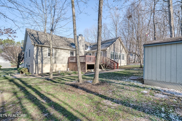 rear view of house with a lawn, a storage shed, and a deck