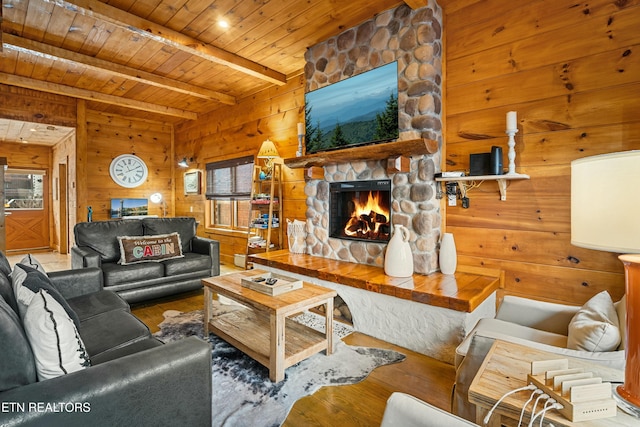 living room with beamed ceiling, a stone fireplace, wooden ceiling, and hardwood / wood-style floors