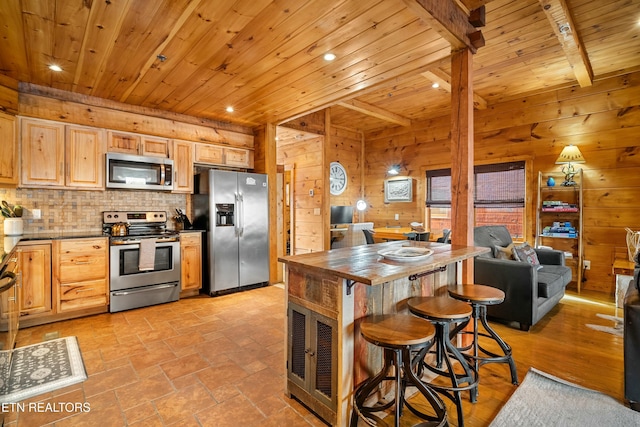 kitchen with appliances with stainless steel finishes, light brown cabinetry, wood ceiling, wooden walls, and beamed ceiling