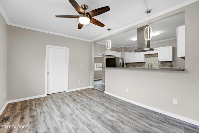 kitchen with white cabinets, island range hood, kitchen peninsula, and stainless steel refrigerator