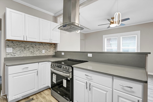 kitchen featuring stainless steel electric stove, island range hood, white cabinets, and pendant lighting