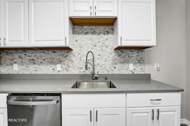 kitchen featuring backsplash, white cabinetry, sink, and stainless steel dishwasher