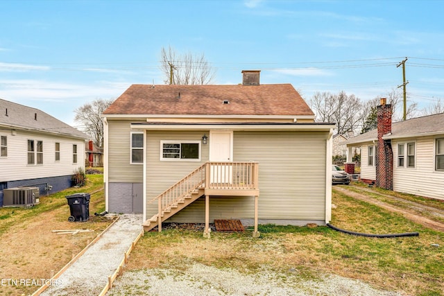 rear view of house with central air condition unit and a lawn