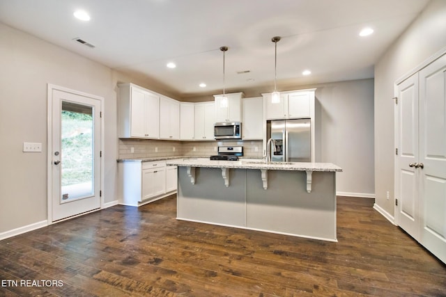 kitchen with white cabinetry, a center island, hanging light fixtures, light stone counters, and appliances with stainless steel finishes