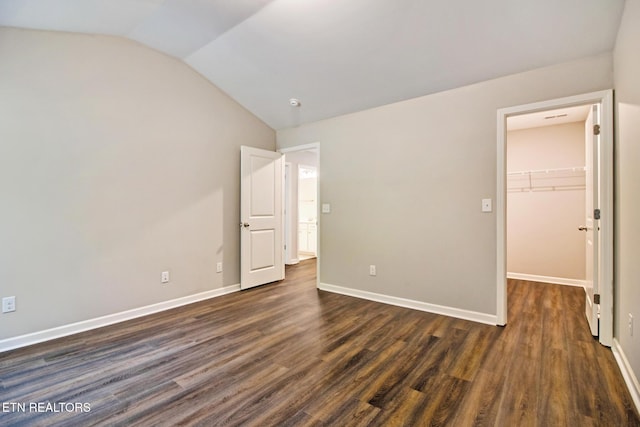 unfurnished bedroom with a walk in closet, dark hardwood / wood-style floors, a closet, and lofted ceiling