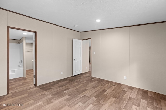 unfurnished bedroom featuring hardwood / wood-style floors, a textured ceiling, and ornamental molding