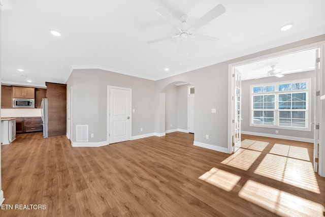 unfurnished living room with ceiling fan, ornamental molding, and light hardwood / wood-style flooring