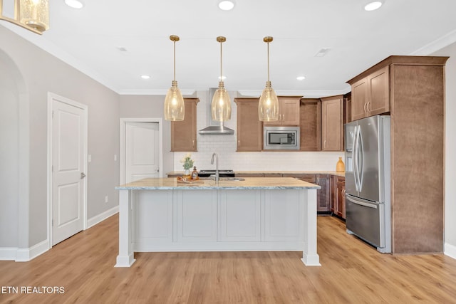 kitchen featuring hanging light fixtures, light stone counters, backsplash, a center island with sink, and appliances with stainless steel finishes