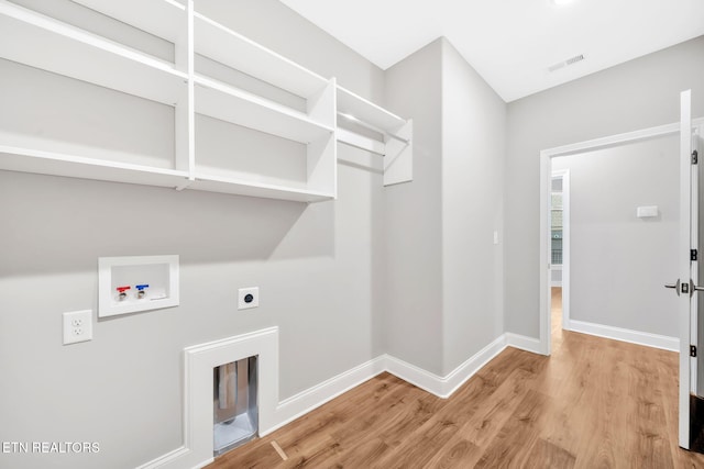 laundry room featuring electric dryer hookup, hookup for a washing machine, and light hardwood / wood-style flooring