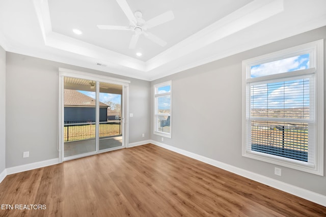 spare room with a tray ceiling, ceiling fan, and hardwood / wood-style floors