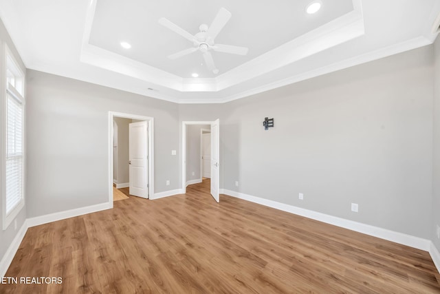 unfurnished bedroom with light hardwood / wood-style flooring, a raised ceiling, ceiling fan, and ornamental molding