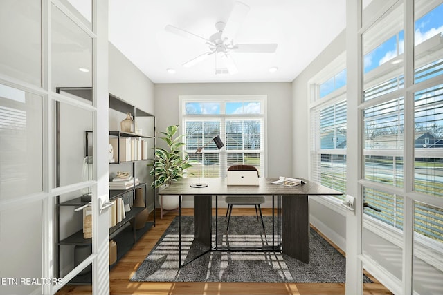 home office with a ceiling fan, baseboards, and wood finished floors