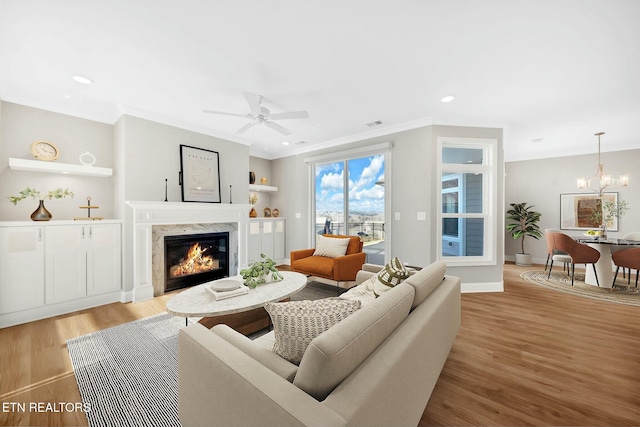 living room featuring ornamental molding, a fireplace, recessed lighting, and light wood-style floors