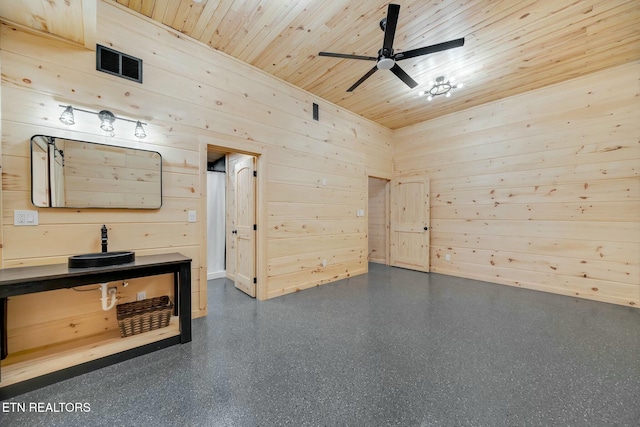 empty room featuring wooden walls, ceiling fan, wood ceiling, and a high ceiling