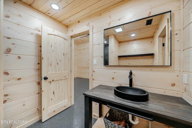 bathroom with wooden walls, sink, and wood ceiling