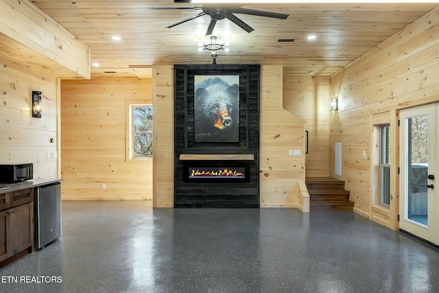 living room featuring ceiling fan, wood ceiling, and wood walls