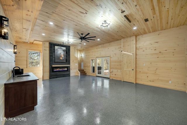 unfurnished living room with a healthy amount of sunlight, wooden ceiling, and wood walls