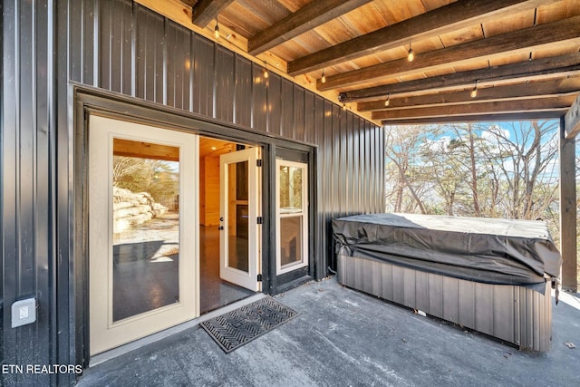 view of exterior entry with a patio and a hot tub