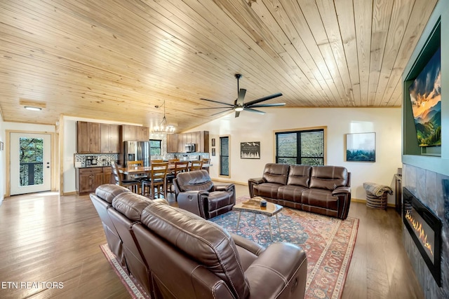 living room featuring hardwood / wood-style floors, lofted ceiling, a tiled fireplace, wood ceiling, and ceiling fan with notable chandelier