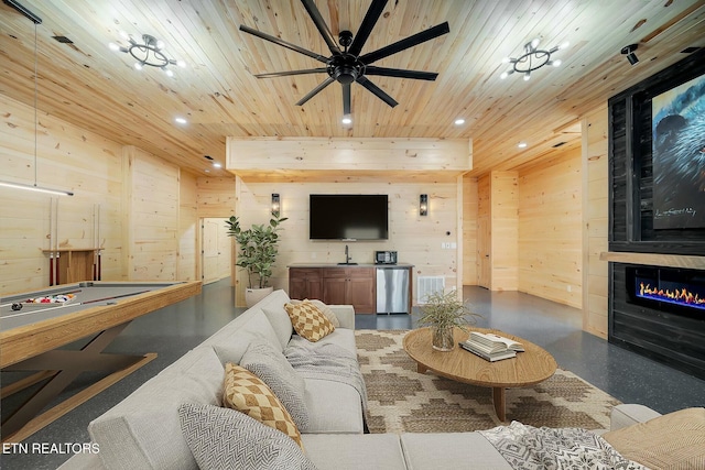 living room featuring wooden ceiling, wooden walls, ceiling fan, a fireplace, and pool table